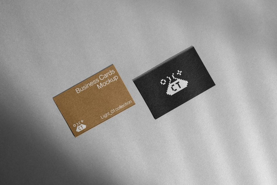 Tan cardstock business card next to black card with pixel logo on gray surface